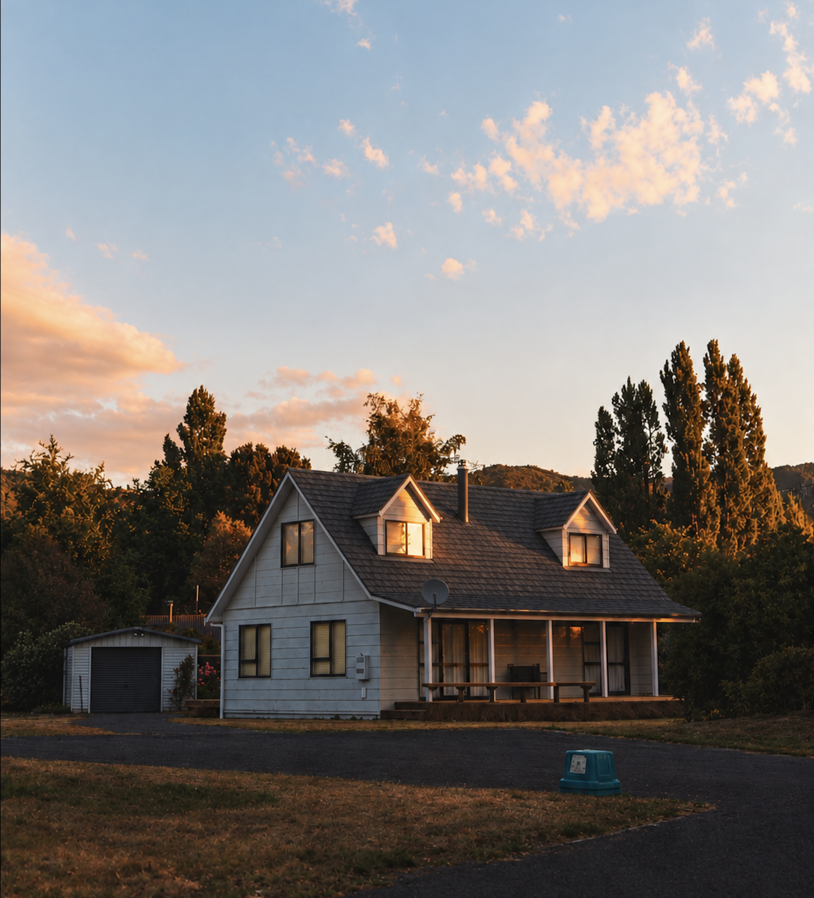 Farmhouse-style home with a shingle roof and detached garage in Grabill, Indiana at sunset.