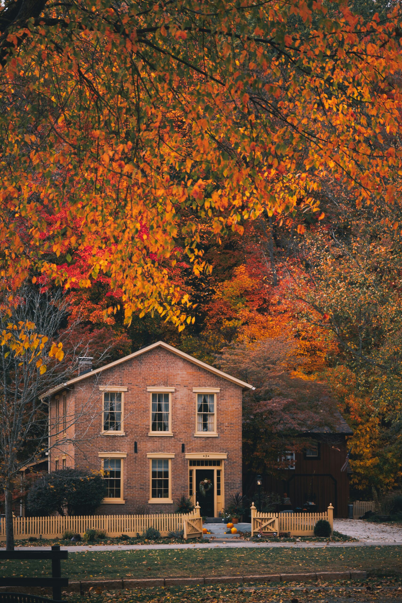 Two-story brick home with a yellow wood fence in Monroeville, Indiana